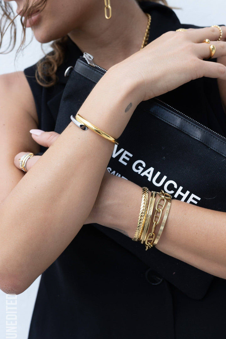 a woman holding a black purse with gold bracelets