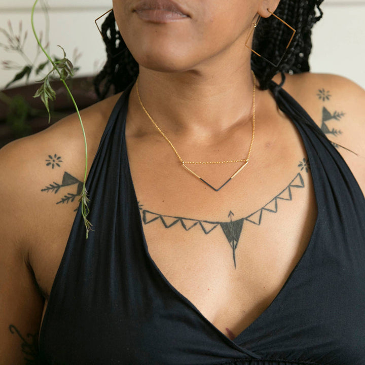 a woman with tattoos on her chest holding a plant