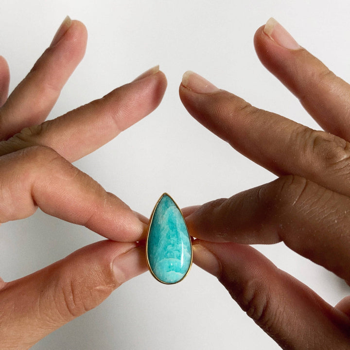 a woman's hands holding a ring with a turquoise stone