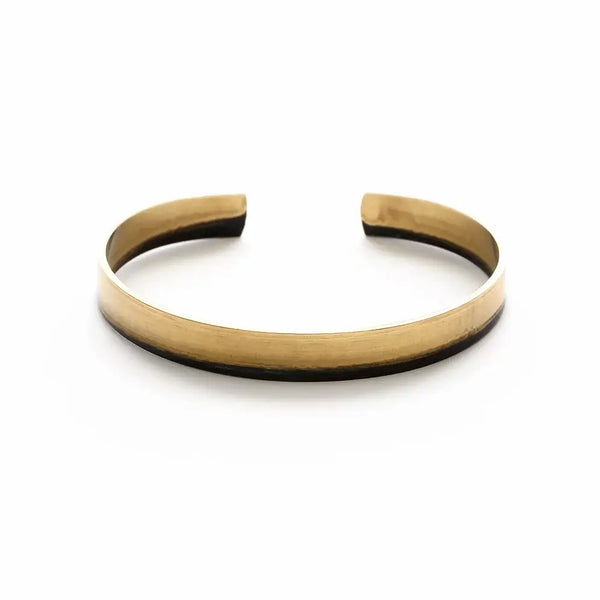 a brass cuff bracelet on a white background