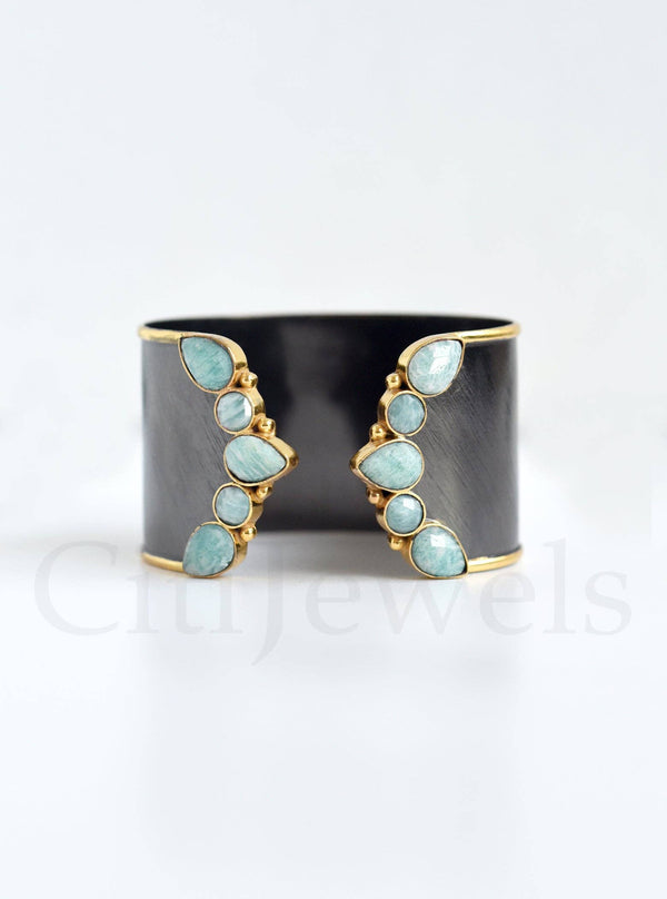 a black and gold cuff with blue stones