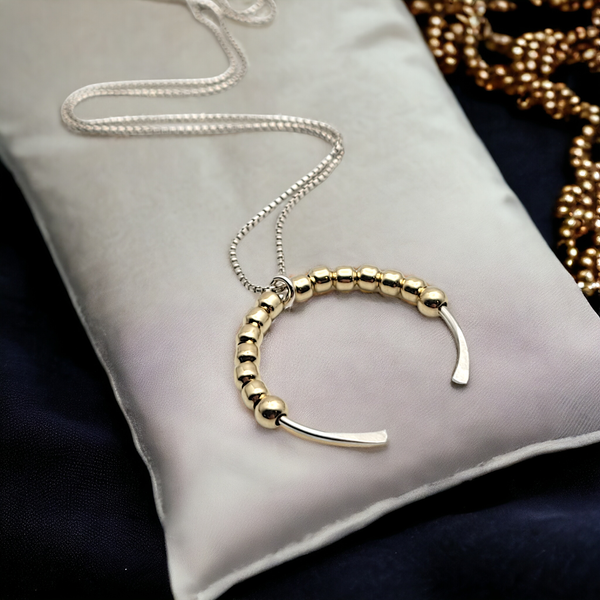 a white pillow with a gold beaded bracelet on it