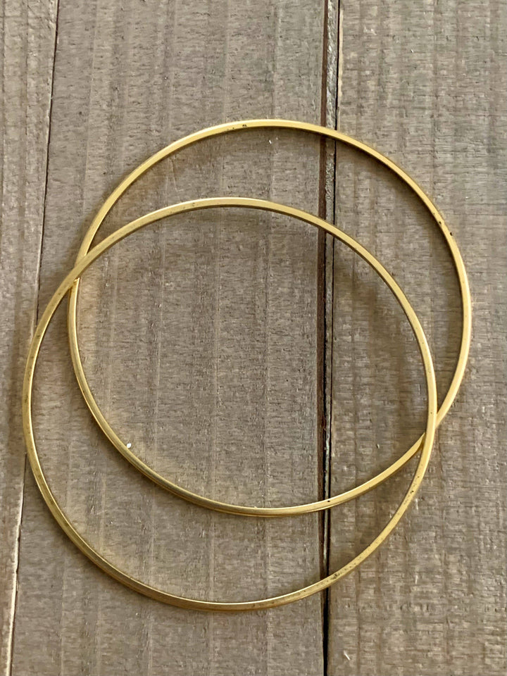 a pair of gold hoop earrings sitting on a wooden surface