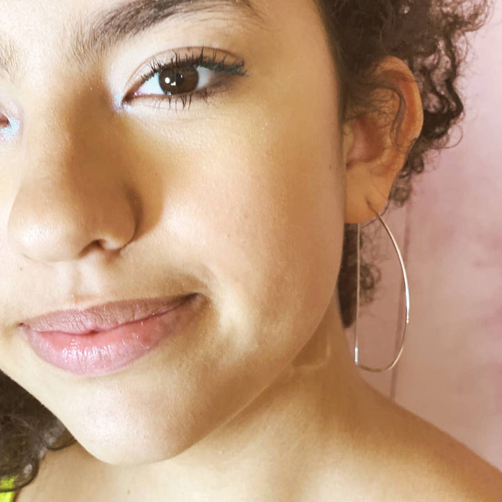 a close up of a person wearing a pair of hoop earrings