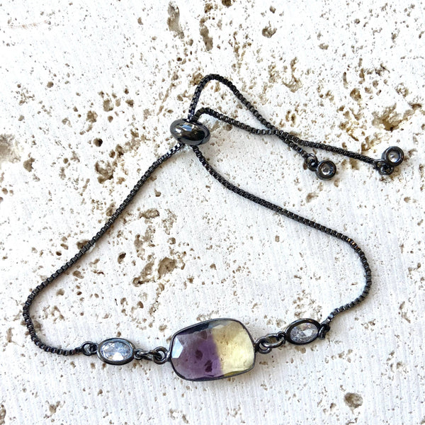 a long necklace with a purple stone on a black chain