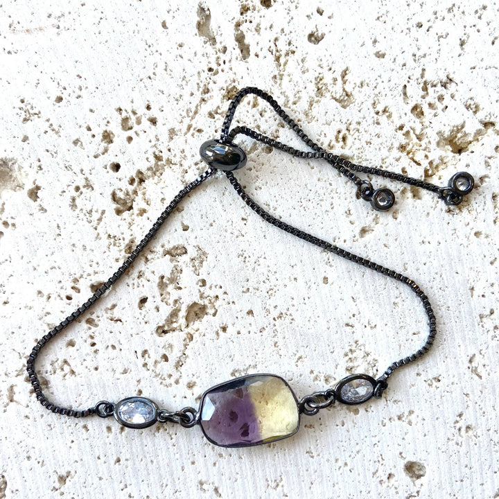 a long necklace with a purple stone on a black chain