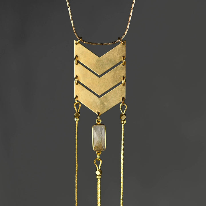 a gold necklace with a long chain and a pendant hanging from it