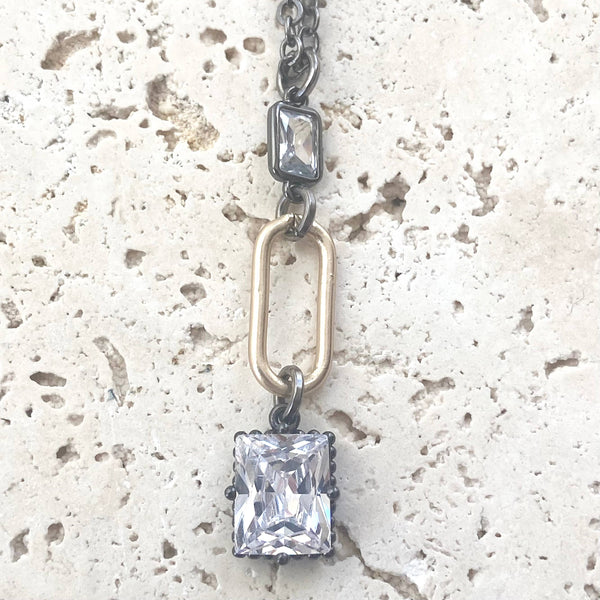 a necklace with a square cut diamond hanging from a chain