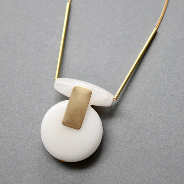 a white and gold necklace on a gray surface