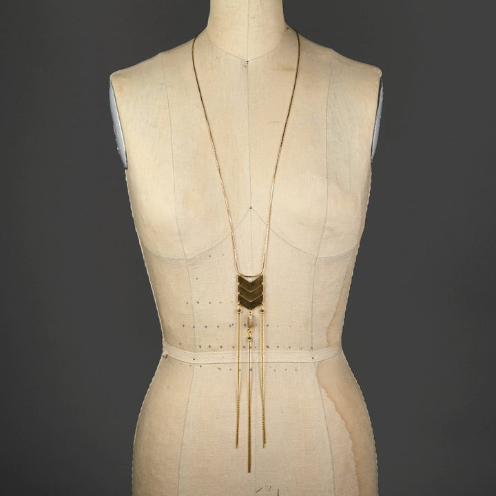 a white mannequin with a gold necklace on it