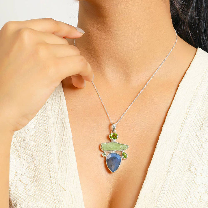 a woman wearing a necklace with a green and blue pendant