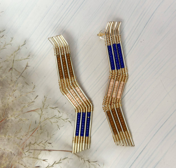 a pair of blue and gold earrings sitting on top of a table