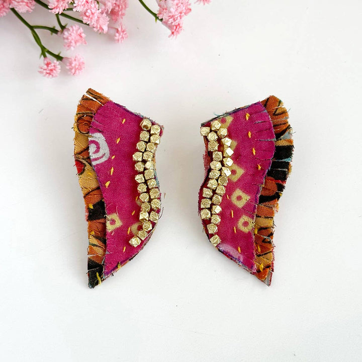 a pair of pink and gold broochies sitting on top of a table