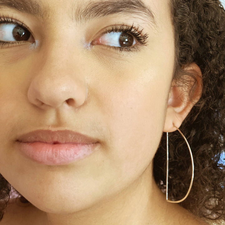 a close up of a person wearing a pair of hoop earrings