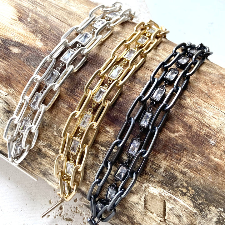 three different types of chain bracelets on a piece of wood