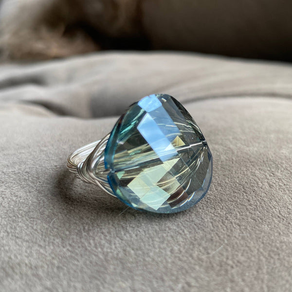 a ring with a blue topaz sits on a cushion